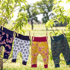 Vêtements évolutifs pour enfants : pantalons évolutifs étendus sur un fil à linge entre deux arbres